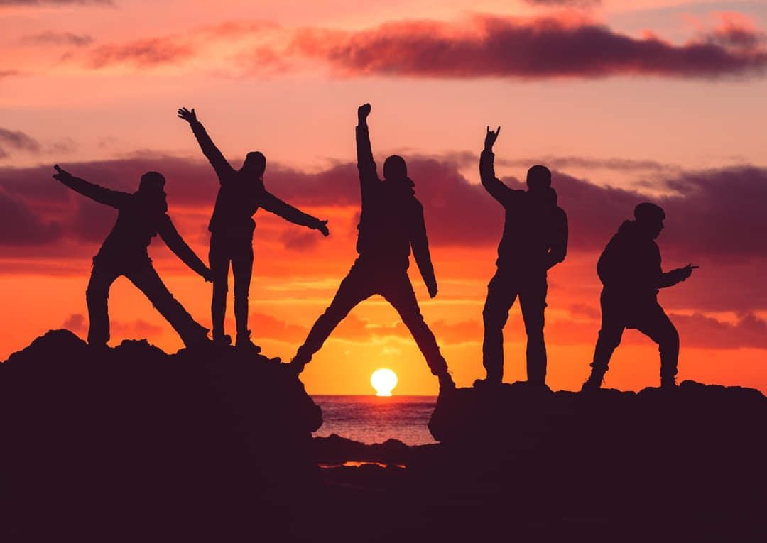 Gruppo di persone che festeggiano insieme su una collina al tramonto